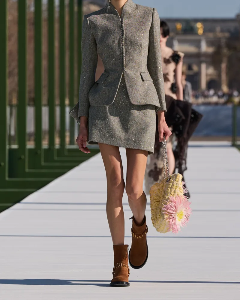 Модель Dior в сером твидовом костюме с мини-юбкой и рыжих замшевых ботинках с пряжкой