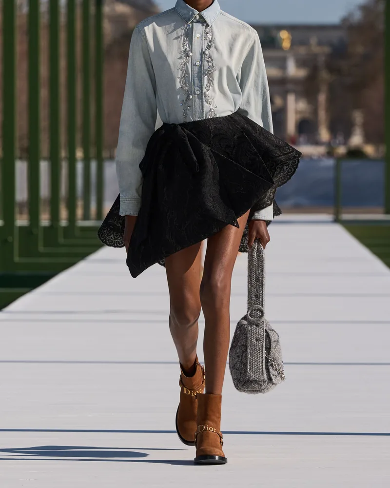 Модель Dior в голубой рубашке, черной пышной юбке и рыжих замшевых ботинках с ремешком на щиколотке