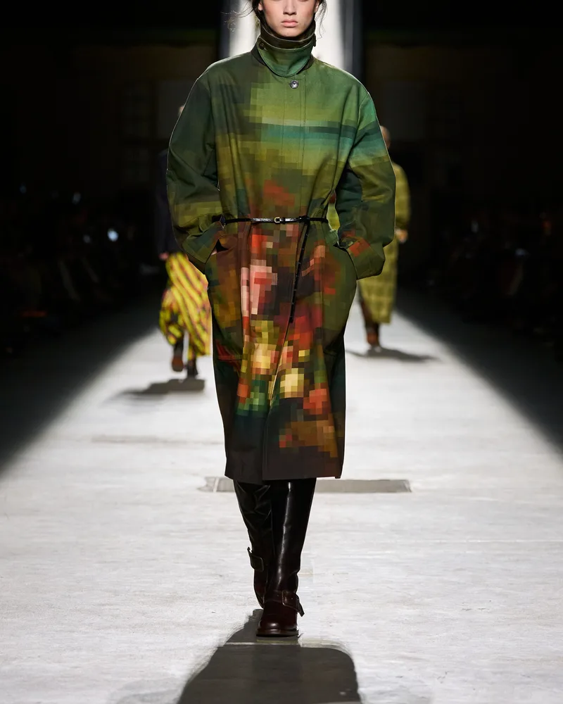 Модель Dries Van Noten в зеленом пальто с принтом и высоких темных сапогах с пряжкой