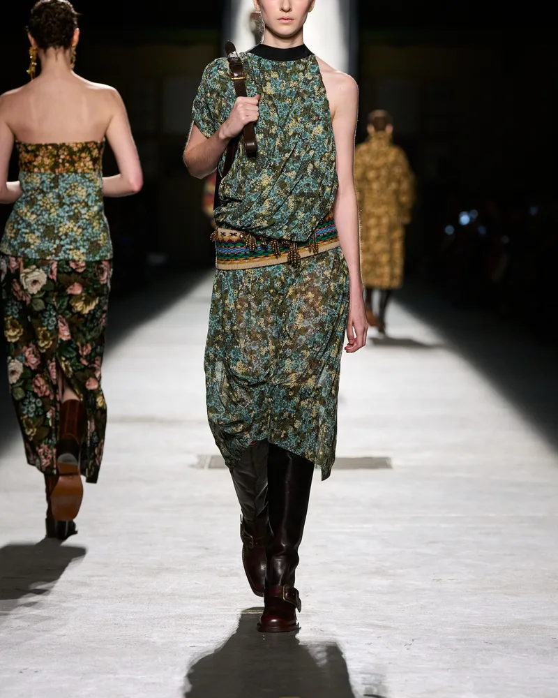 Модель Dries Van Noten в платье с цветочным принтом, поясом и высоких сапогах с пряжкой