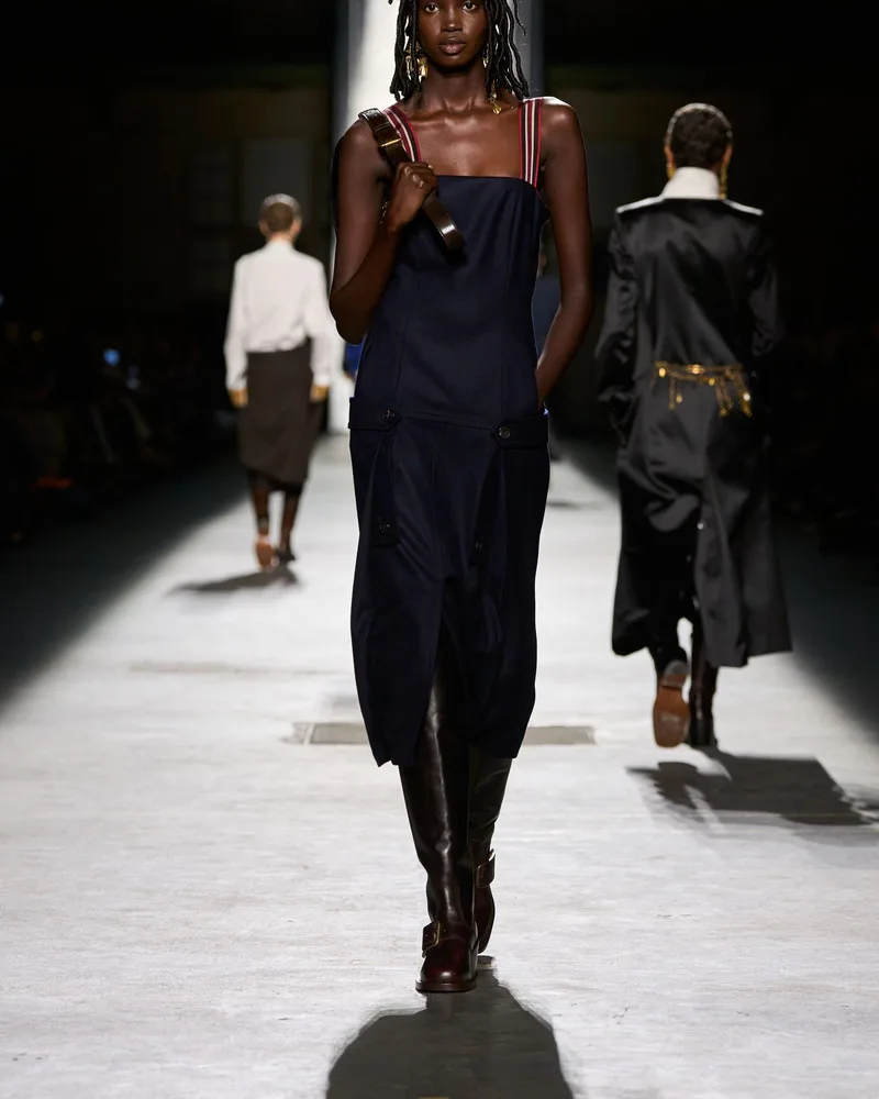 Модель Dries Van Noten в темно-синем платье-комбинации и высоких коричневых сапогах с ремешком на щиколотке