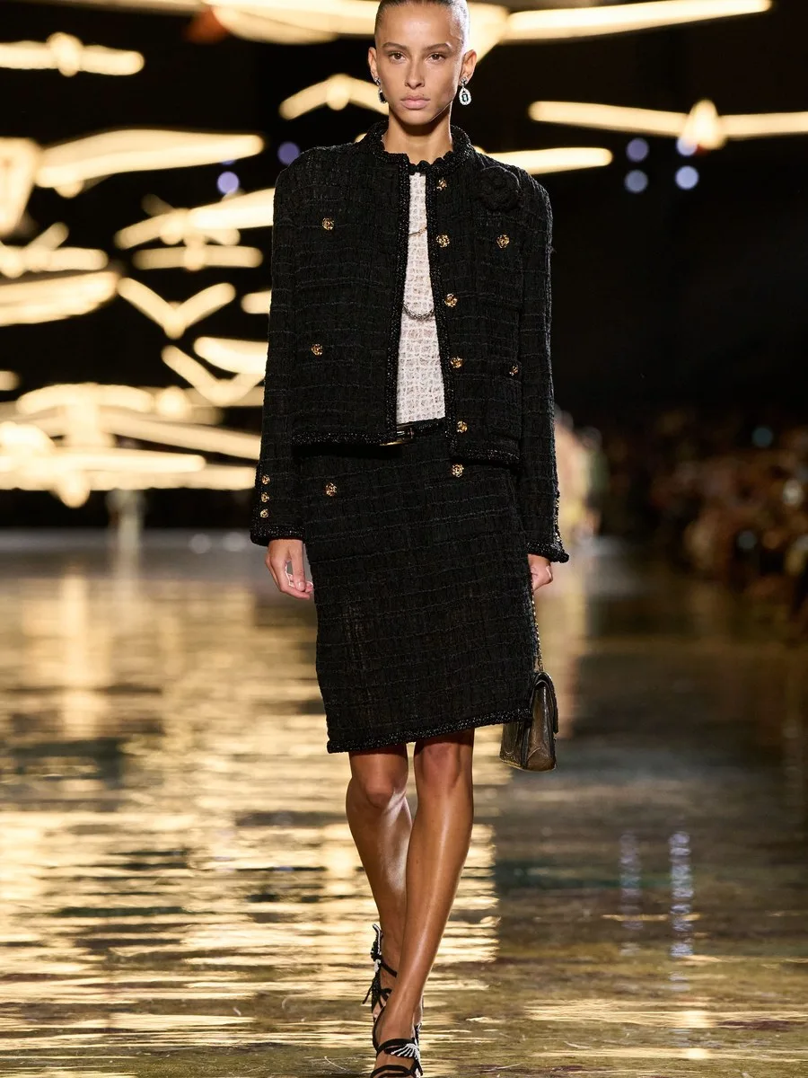 Финальный образ Chanel весна-лето 2027: черный твидовый жакет без воротника, юбка-карандаш и сумка 2.55