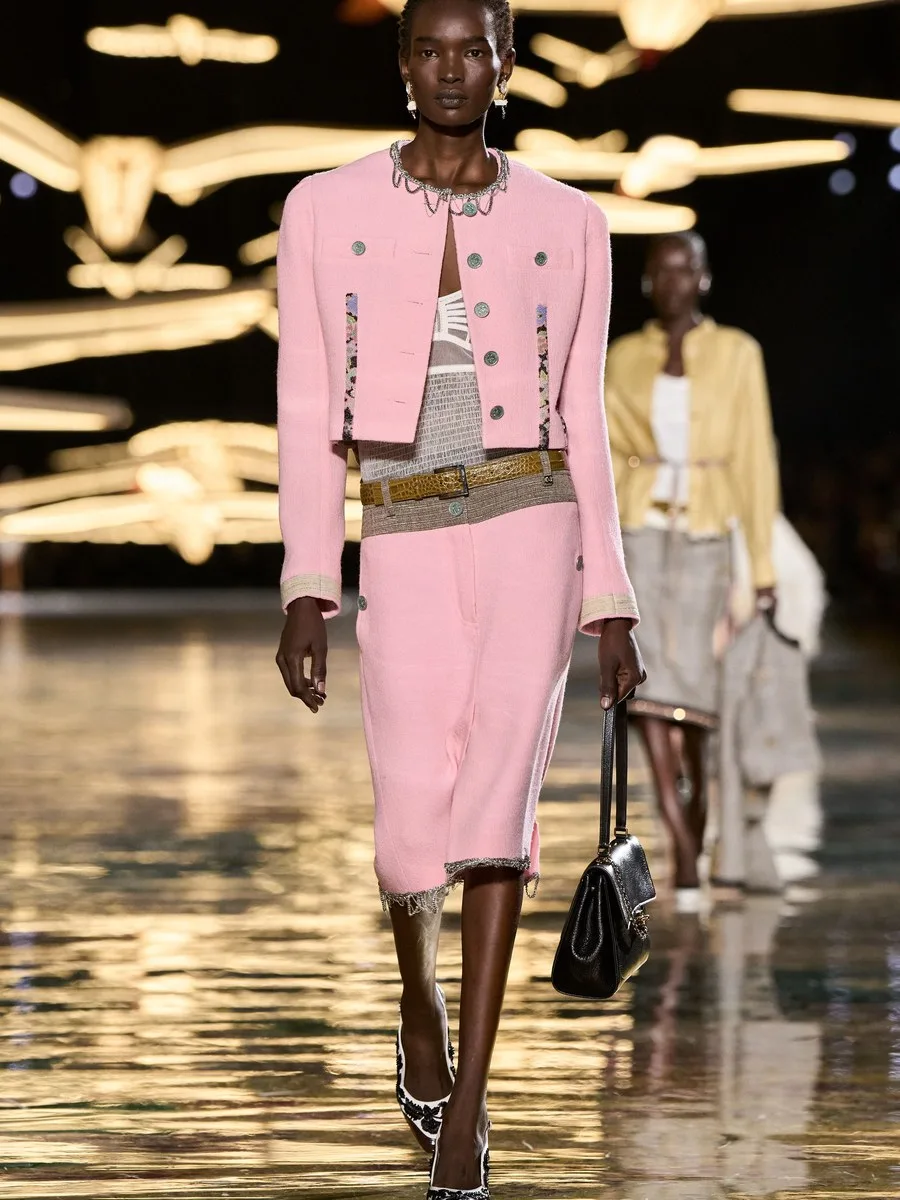 Розовый жакет и юбка Chanel с черной стеганой сумкой-клапаном и бежевым поясом