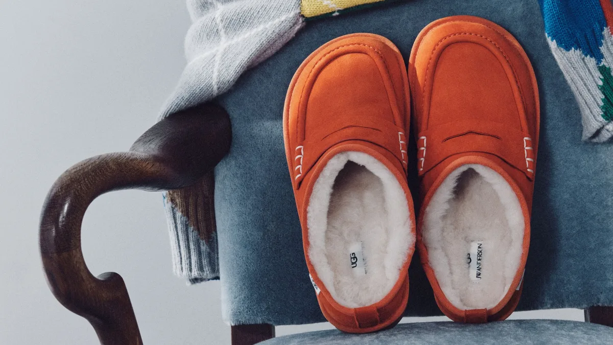Оранжевые замшевые лоферы UGG x JW Anderson с белой овчиной внутри на синем бархатном кресле