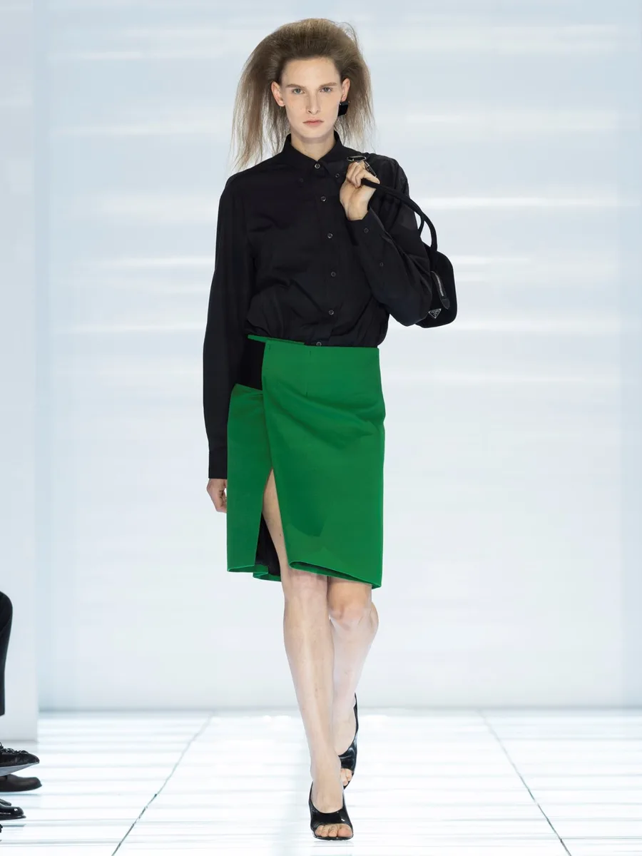 Зеленая юбка до колена с разрезом спереди и черная рубашка, Prada весна-лето 2027